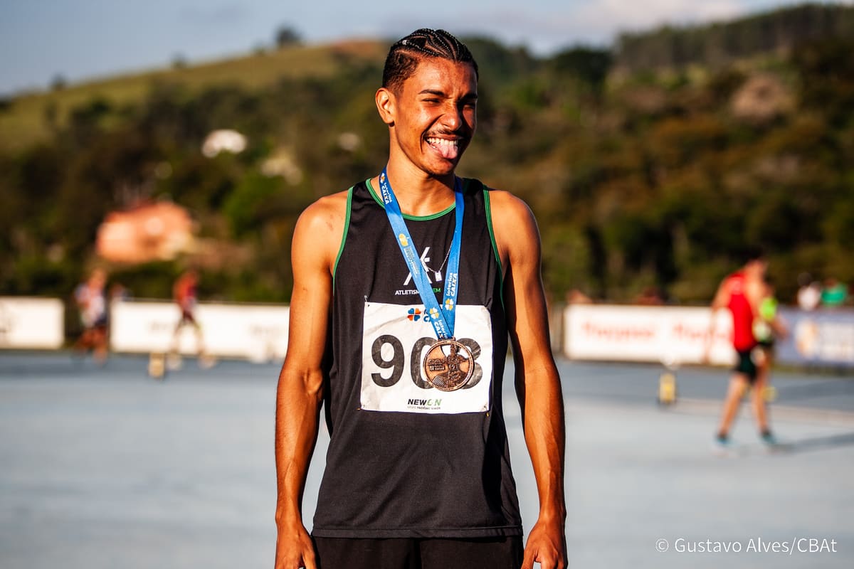 Atleta da Atletismo-UEM posando com medalha de bronze ao pôr do sol