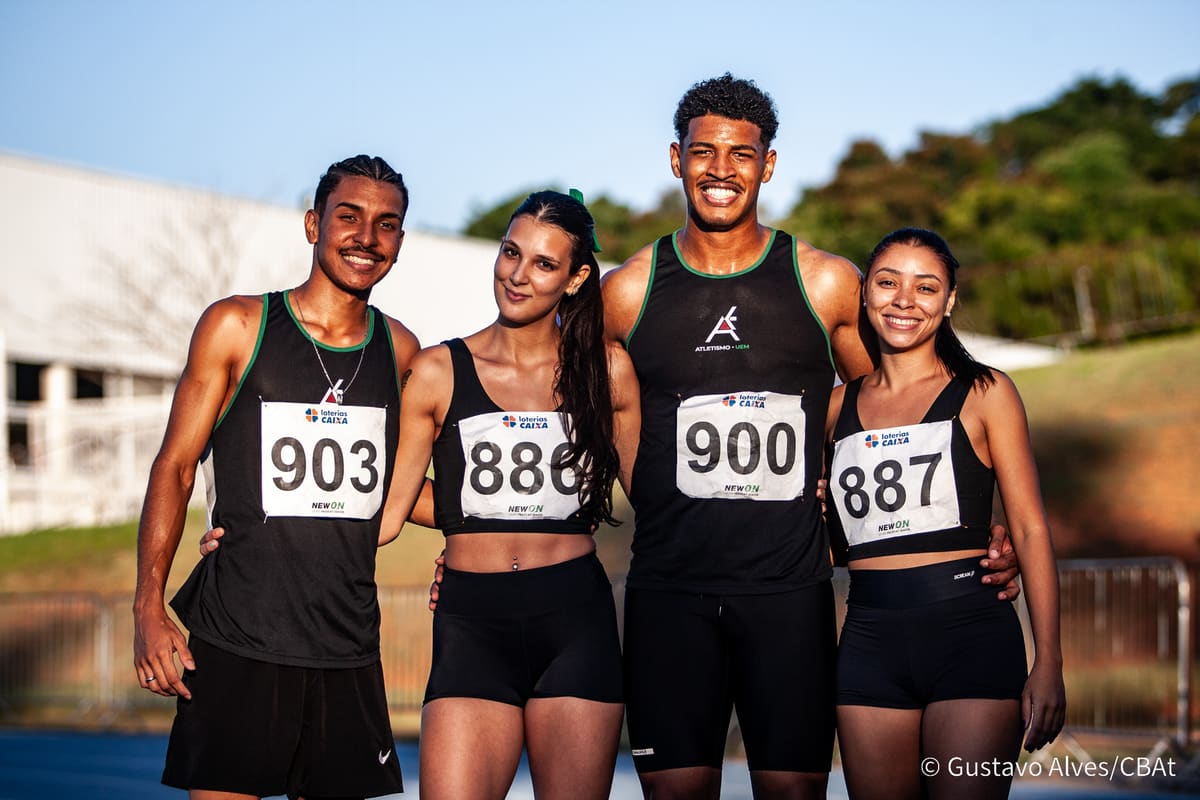 Quatro atletas da Atletismo-UEM posando juntos com números de peito