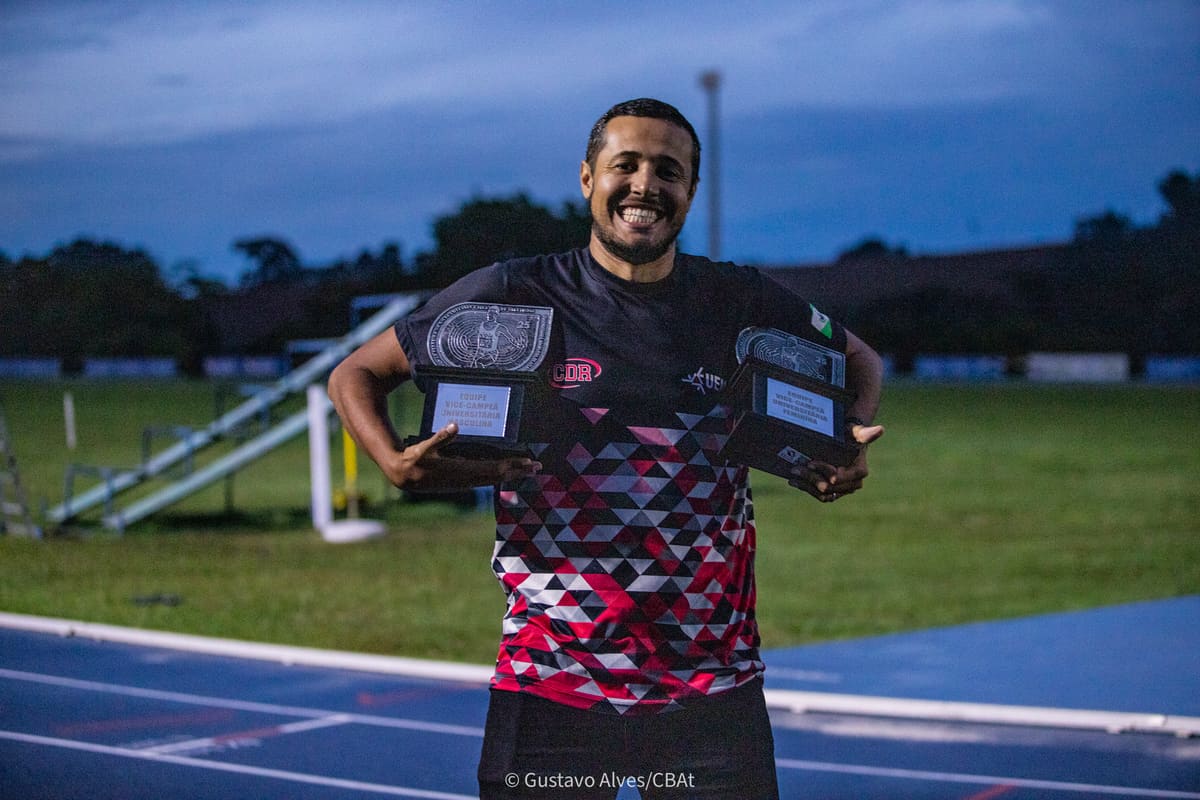 Técnico da Atletismo-UEM segurando os troféus de vice-campeão universitário masculino e feminino no Troféu Adhemar 2025
